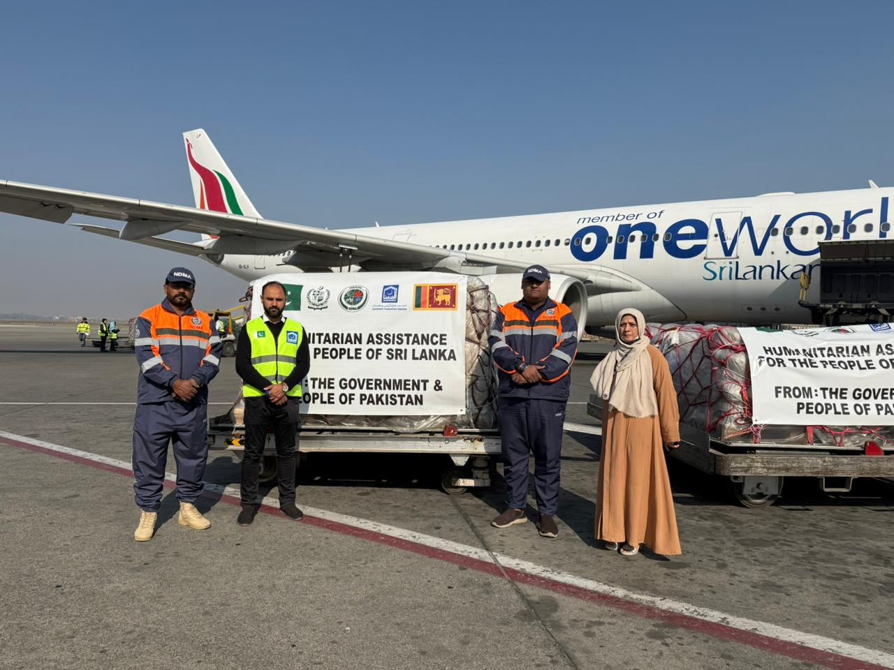 In this handout photo, taken and released by Pakistan's National Disaster Management Authority (NDMA) on December 8, 2025, officials gesture for a group photograph as Pakistan dispatches humanitarian aid to calamity-hit Sri Lanka, at the Allama Iqbal Inte
